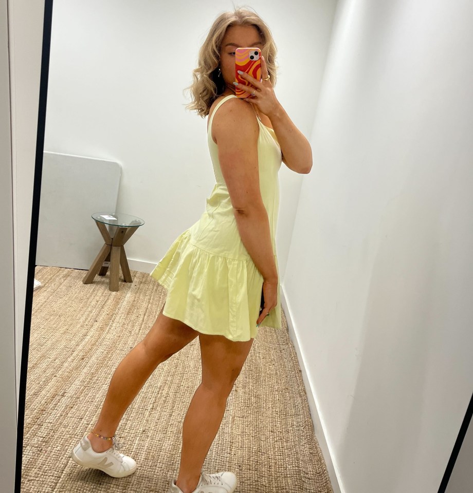 Woman in pale yellow sundress taking a selfie.