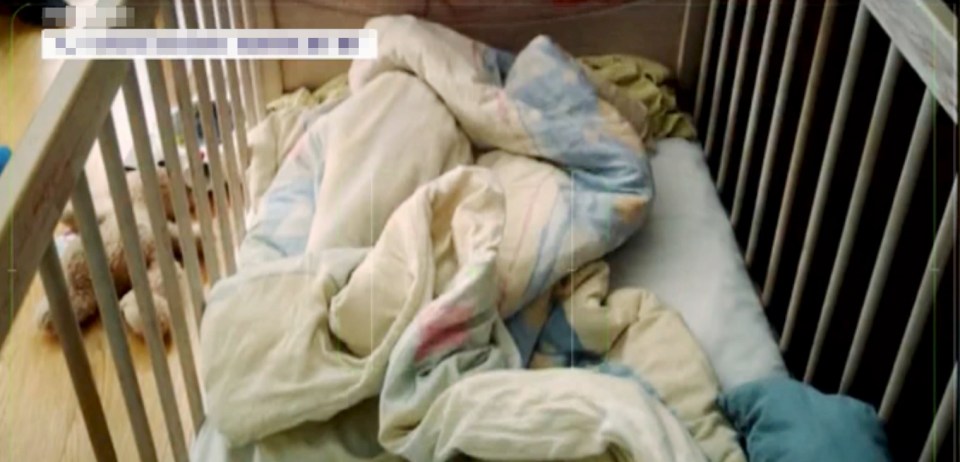Interior of a crib with bedding and a stuffed animal.