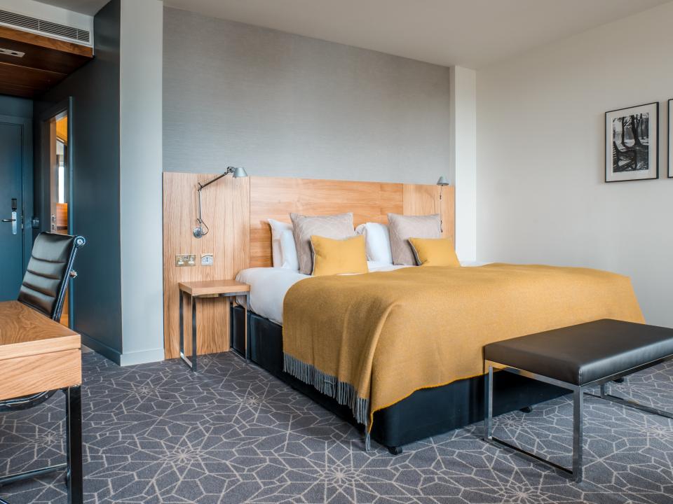 Hotel room with a king-size bed and a work desk.