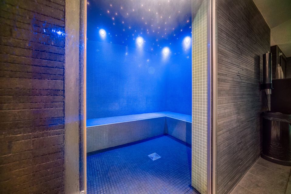 Steam room with blue tile and a built-in bench.