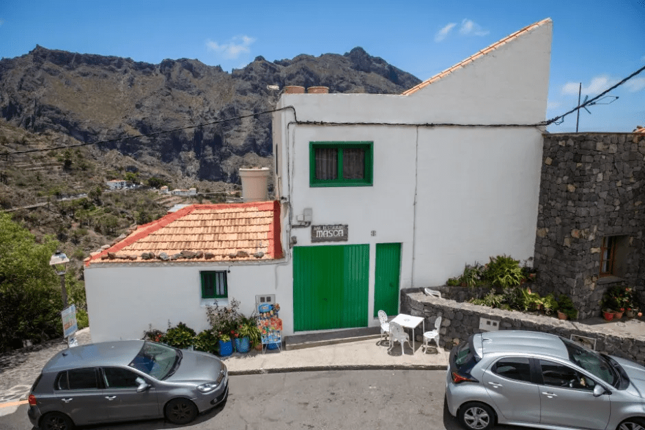 White building with green doors in a mountainous village.