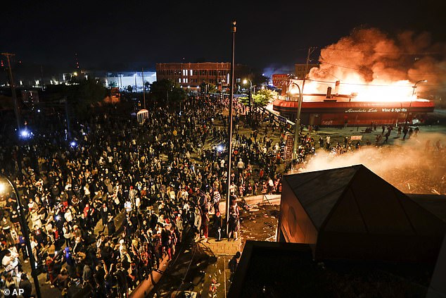 Protestors demonstrate outside of the burning Minneapolis 3rd Police Precinct in Minneapolis on May 28, 2020
