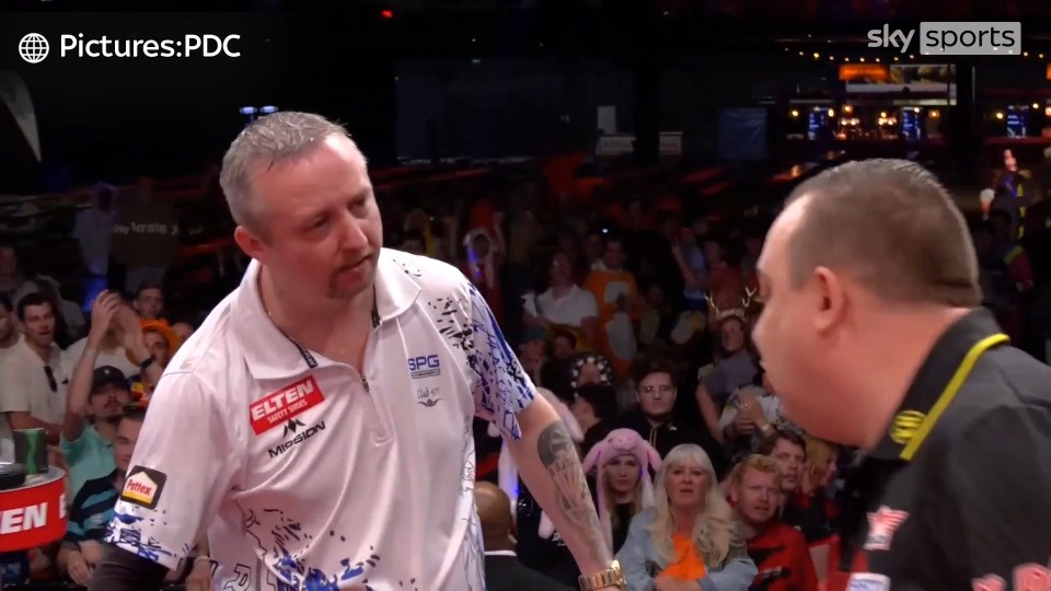 Two darts players arguing on stage.