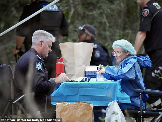 An officer is pictured sitting across from an investigator dressed in forensic coveralls on Saturday. The national park is located about an hour's drive from Bundaberg Airport