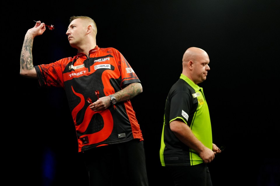 Nathan Aspinall throwing a dart during a darts match.