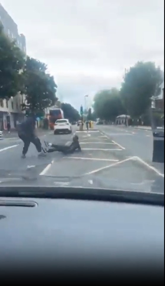 A street fight where a person is kicked while lying on the ground.