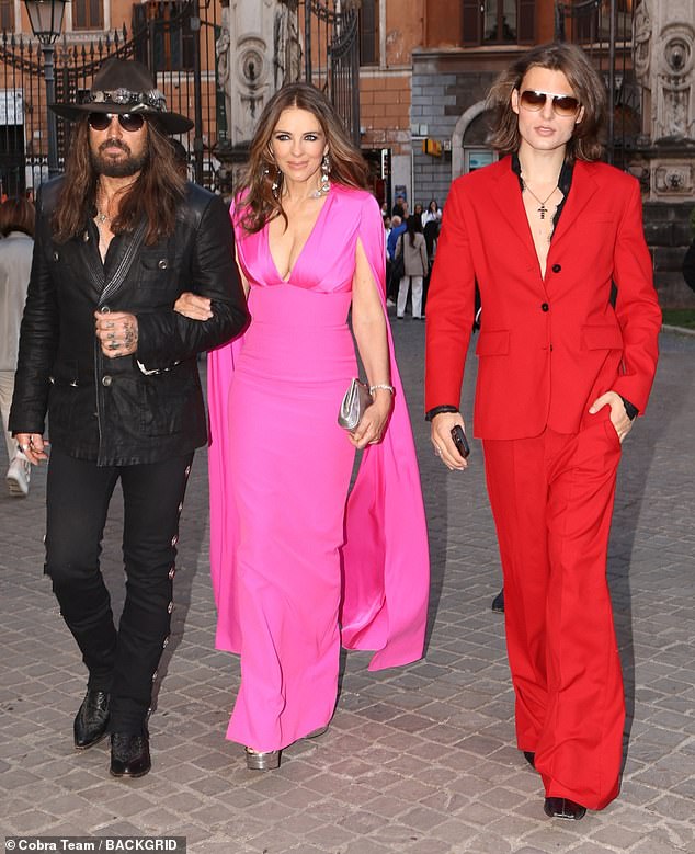 The lovebirds were supported on their first public outing by Elizabeth's lookalike son Damian (R) who was also dressed to impress