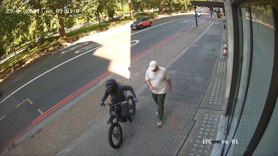 CCTV image of a phone theft: A man on an electric bike snatches a phone from a pedestrian.