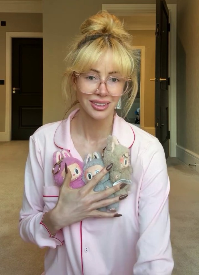 Woman in pajamas holding three small plush toys.