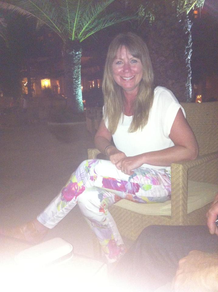 Woman sitting outdoors at night wearing floral pants.