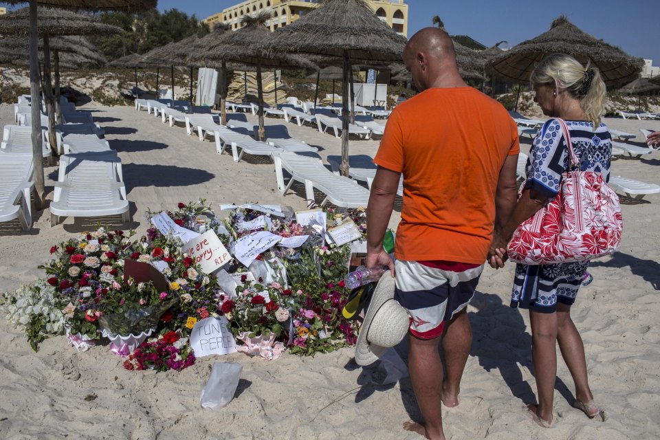 Tourists paying respects at a beach memorial.