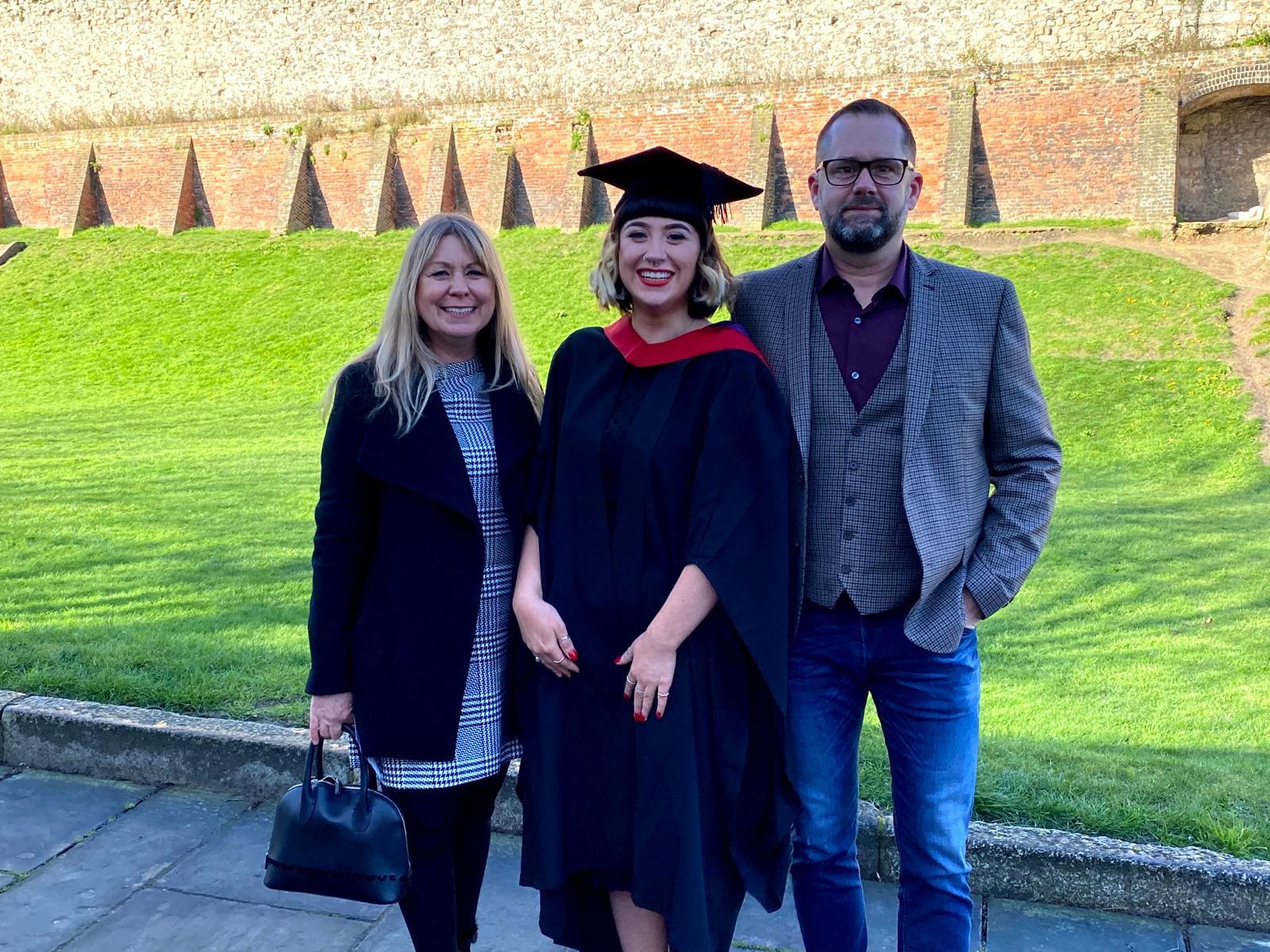 Krystal in cap and gown with parents Sharon and Dave Simes