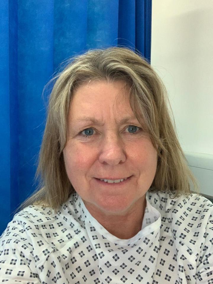 Woman in hospital gown smiling at the camera.