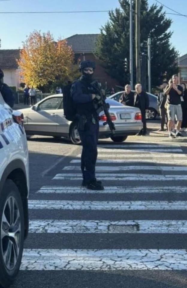 Armed police officer standing at a crosswalk during a lockdown at a Melbourne shopping center.