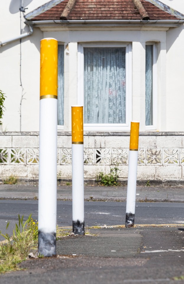 Three bollards painted to resemble cigarettes.