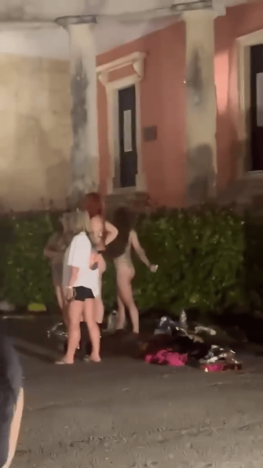 Three partially nude women near a building.