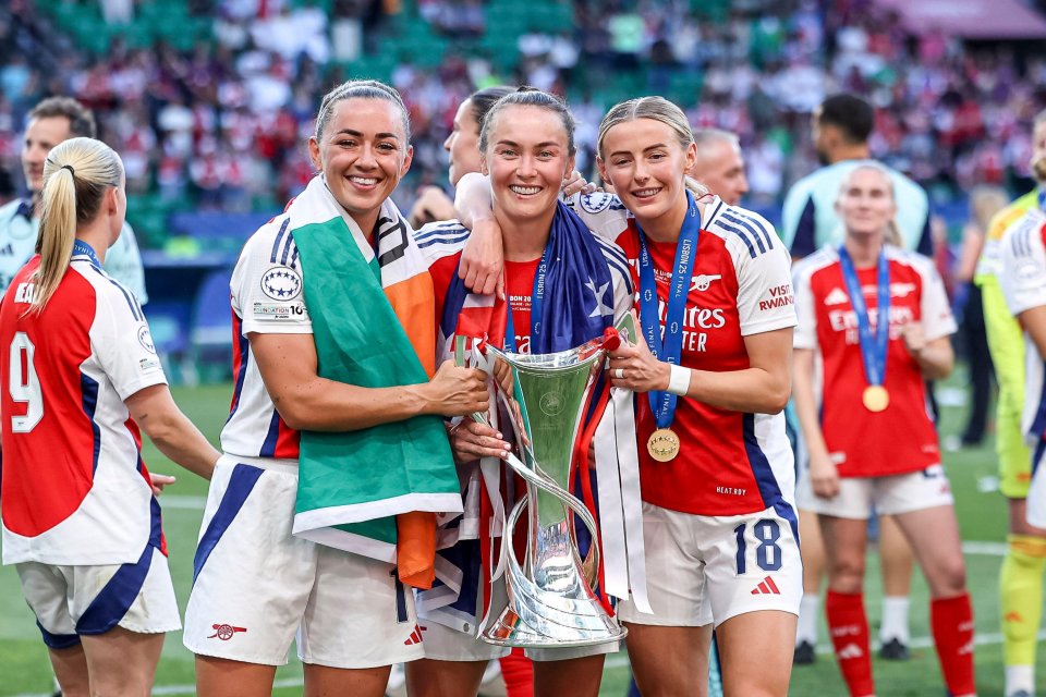 Arsenal FC players celebrating a victory with the trophy and medals.