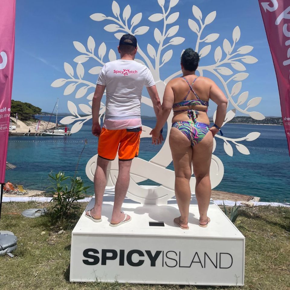 Couple standing in front of a SpicyIsland sign.