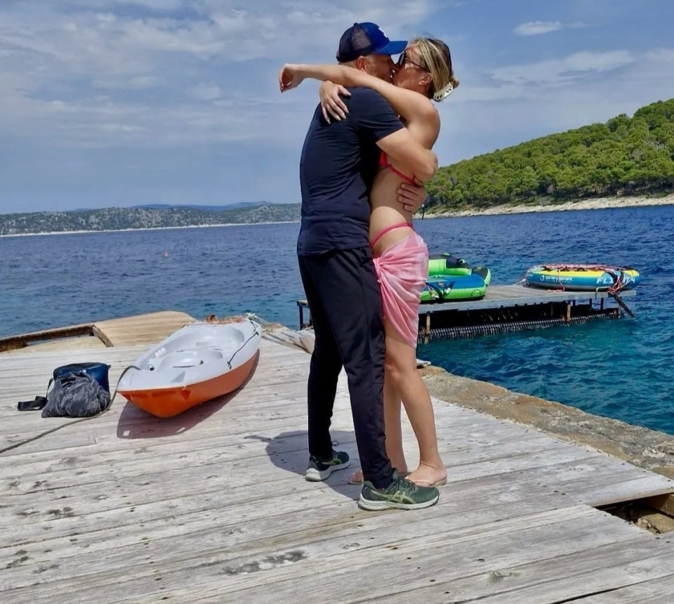 Couple embracing on a dock by the sea.