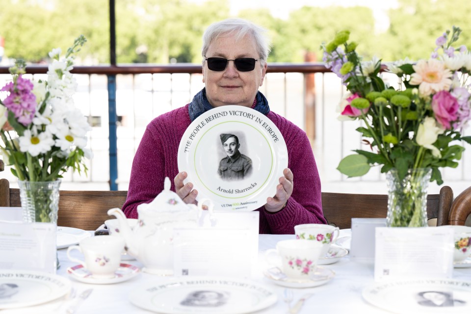 Woman holding commemorative plate of WWII hero Arnold Sharrocks.