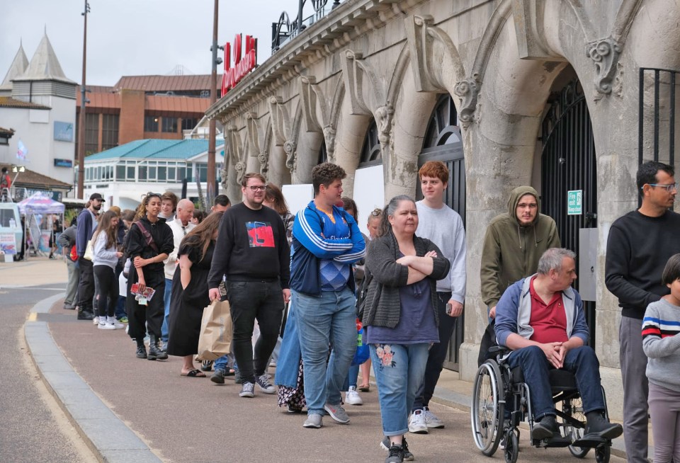 Long queue of people waiting outside a fish and chip shop.
