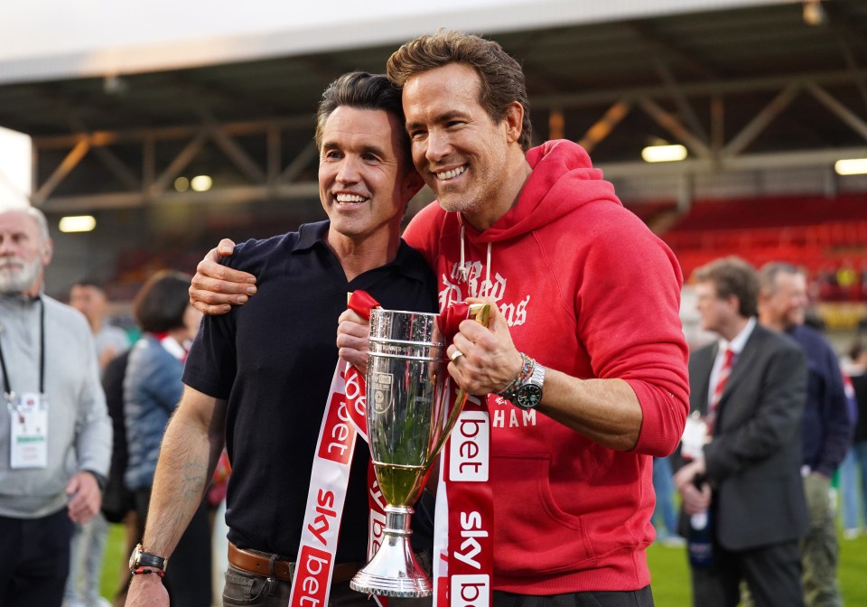 Rob McElhenney and Ryan Reynolds holding a trophy.