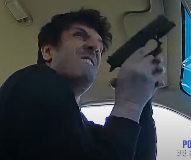 Video still of a man holding a gun in his car during a traffic stop.