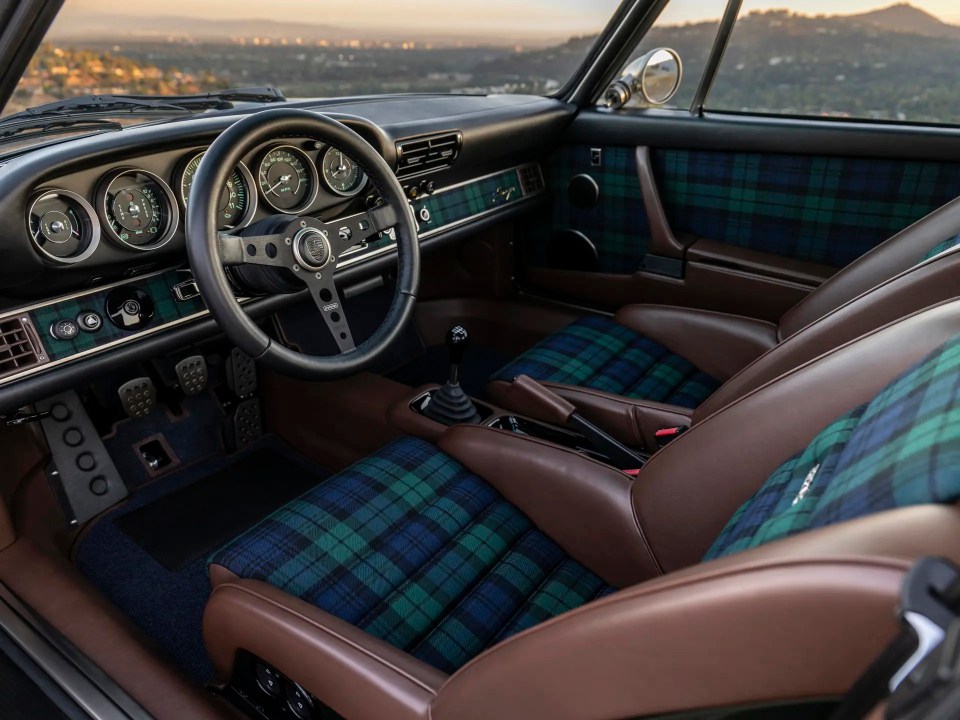 Interior of a Porsche 911 with plaid seats and brown leather accents.