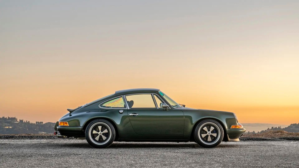 Profile view of a dark green Porsche 911 at sunset.