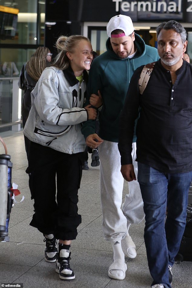She held on to his arm as they made their way through the terminal
