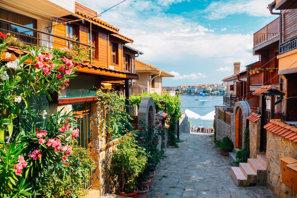 Stone street in Sozopol, Bulgaria, with colorful houses and flowers.