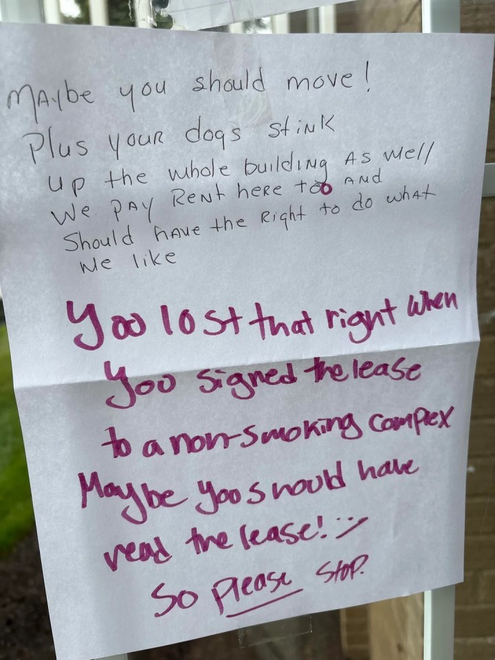 Handwritten note accusing dog owners of causing building odors and demanding they stop.