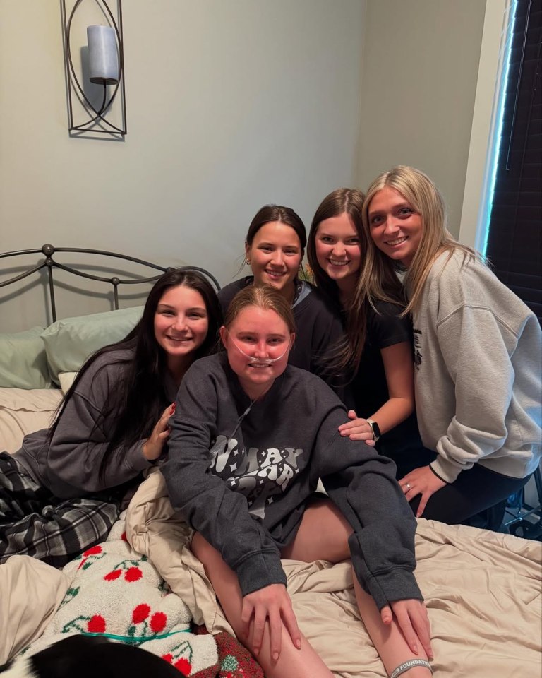 A young woman with friends in a bedroom.