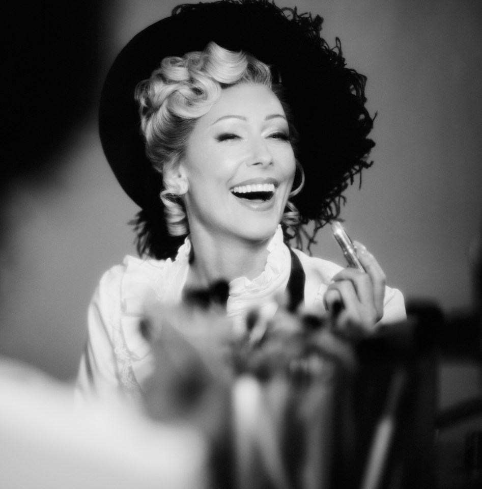 Black and white photo of Faye Tozer applying lipstick.