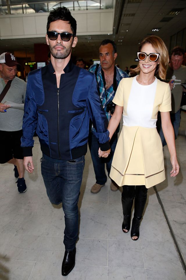 Cheryl Fernandez-Versini and Jean-Bernard Fernandez-Versini holding hands at an airport.