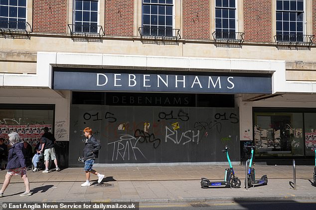 Men with cans of alcohol stood outside the graffitied front of Debenhams when MailOnline visited the store