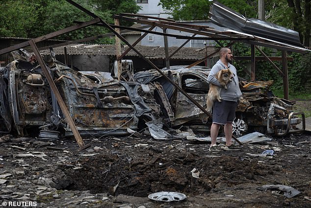 An Odesa resident with a dog stands next to cars destroyed in a residential area during a Russian drone strike
