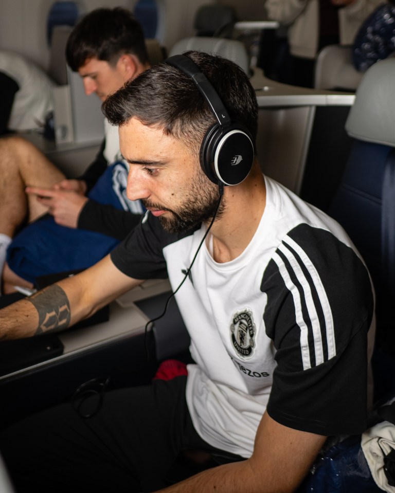 Bruno Fernandes of Manchester United wearing headphones on a plane.