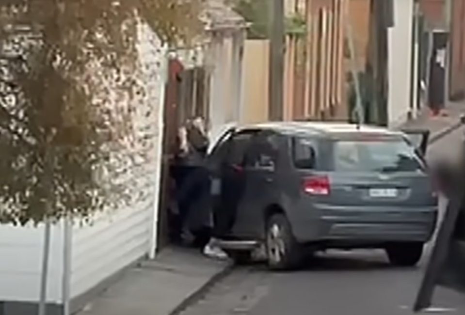 A police officer apprehending a woman next to a car.