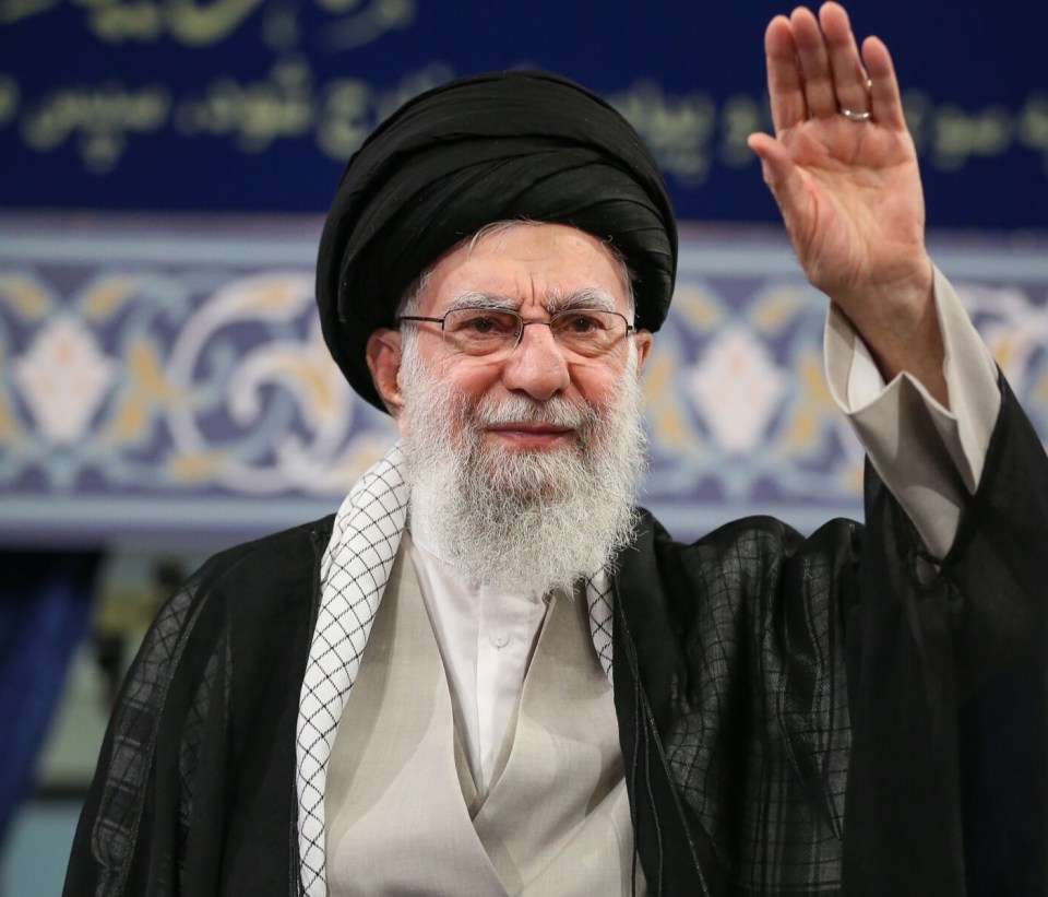 Ayatollah Ali Khamenei waving at a ceremony.