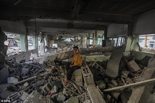 A displaced Palestinian boy sits at the destroyed building of Al Jerjawi school following Israeli air strike on the Gaza City site on May 26
