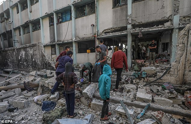 Men and children look through the rubble after the bombing of the Al Jerjawi school in Gaza City on May 26