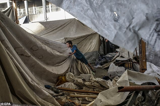 An internally displaced Palestinian boy inspects his family destroyed tent in Al Jerjawi school following Israeli air strike in the Al Daraj neighborhood in Gaza City