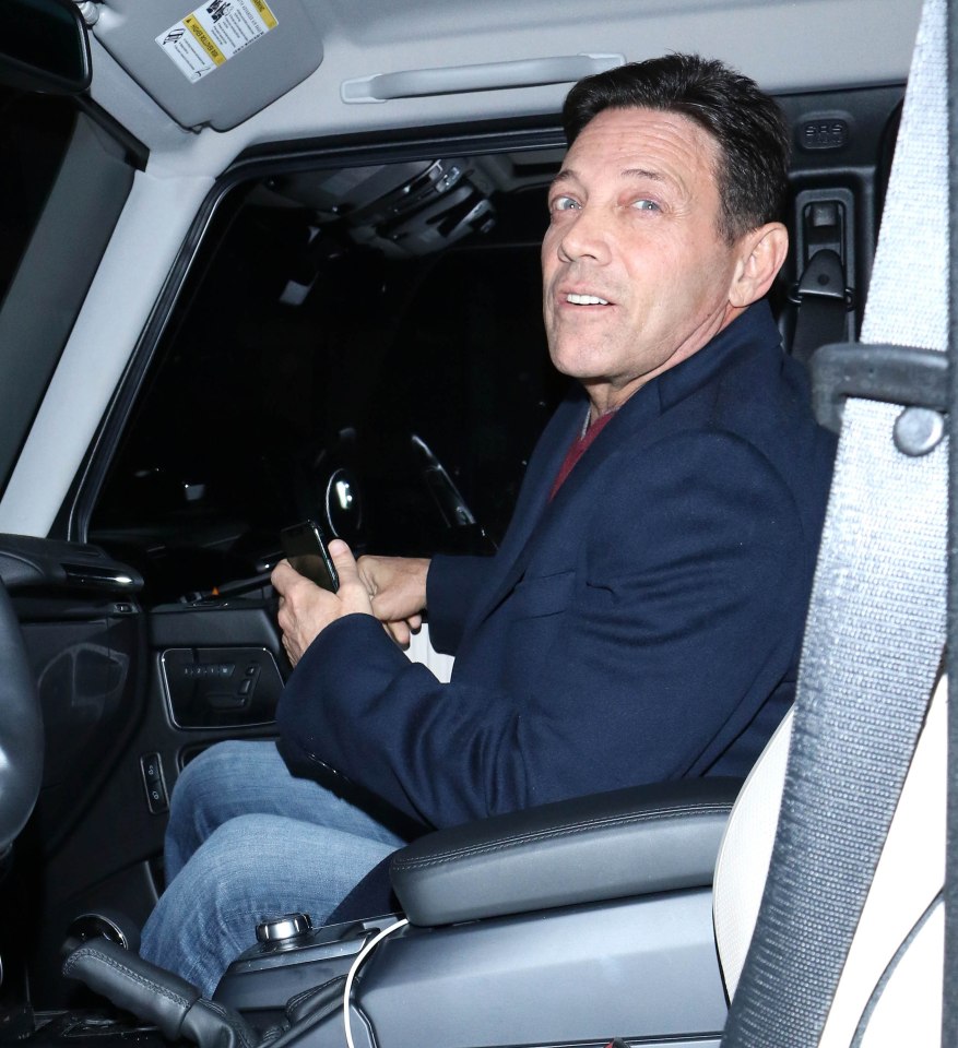 Jordan Belfort in a car, looking over his shoulder.