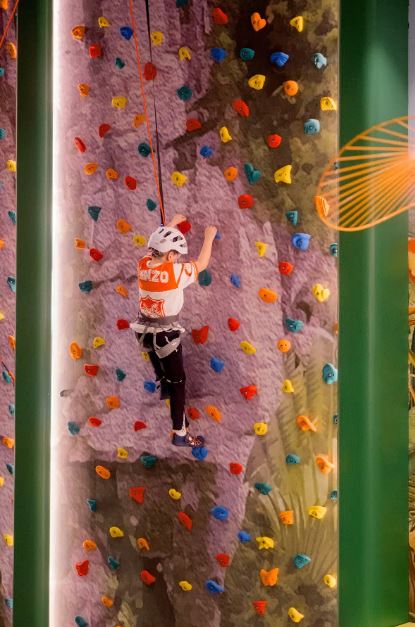 Child climbing a colorful indoor rock wall.