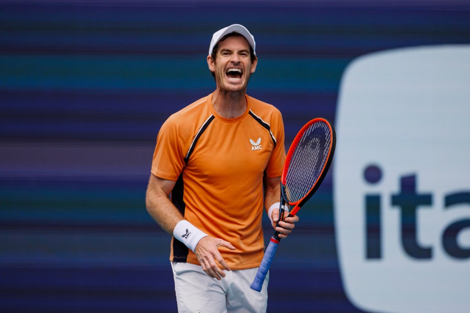 Andy Murray laughing while holding a tennis racket.