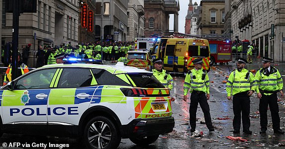 Police officers stand on duty at a cordon at the entrance to Water Steet, at the scene of an incident, on the sidelines of an open-top bus victory parade for Liverpool's Premier League title win, in Liverpool, north-west England on May 26, 2025. (Photo by Darren Staples / AFP) (Photo by DARREN STAPLES/AFP via Getty Images)