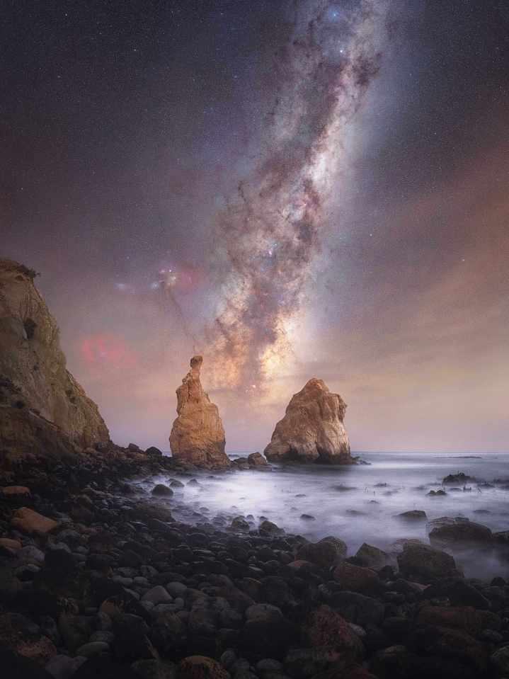 Astrophotography of the Milky Way over a rocky coast.