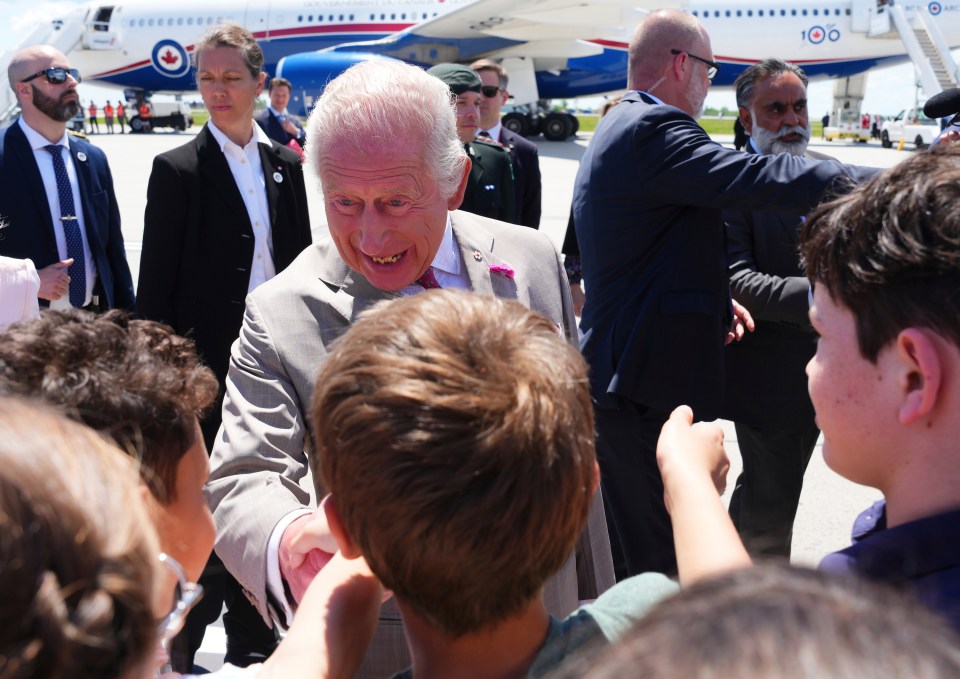 King Charles greeting school children at an airport.
