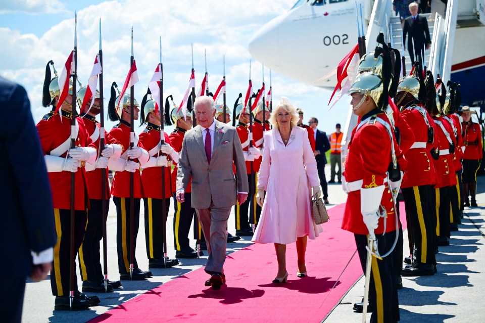 King Charles and Queen Camilla arriving at an airport in Canada, greeted by a military honor guard.